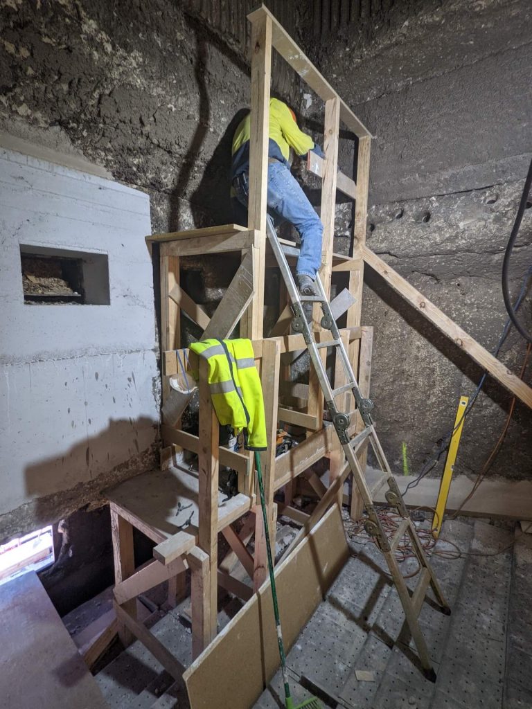 A timber scaffold in front of a refractory wall in the middle of repair